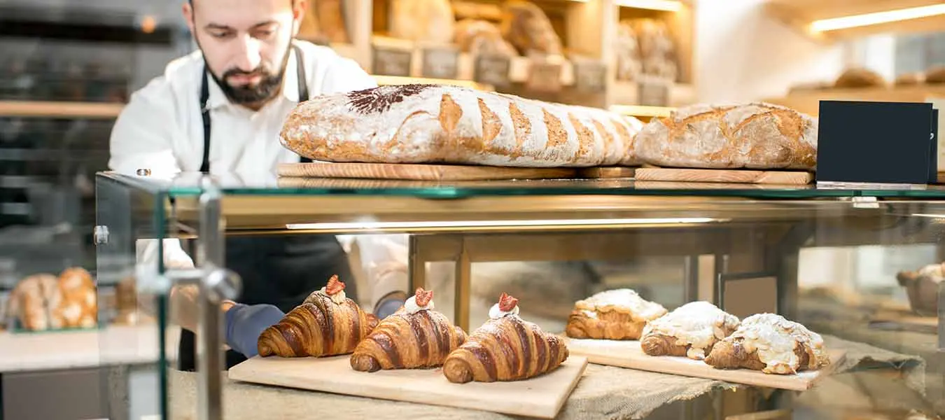Baker placing baked goods in a case 1350